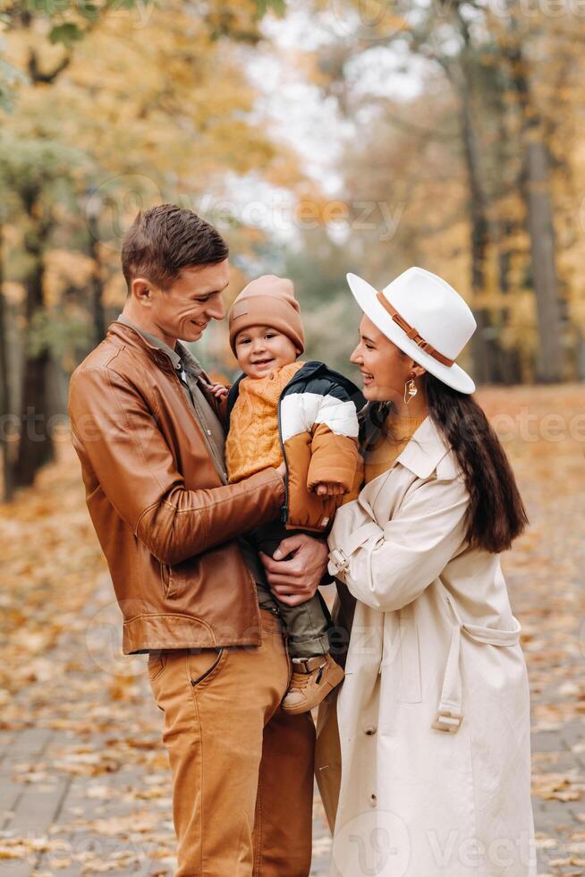 Father and mother with son walking in the autumn Park. A family walks in the Golden autumn in a nature Park. photo