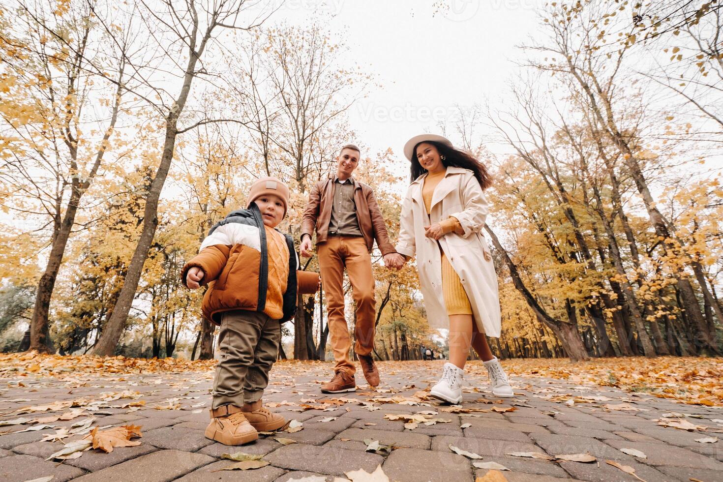 Father and mother with son walking in the autumn Park. A family walks in the Golden autumn in a nature Park. photo
