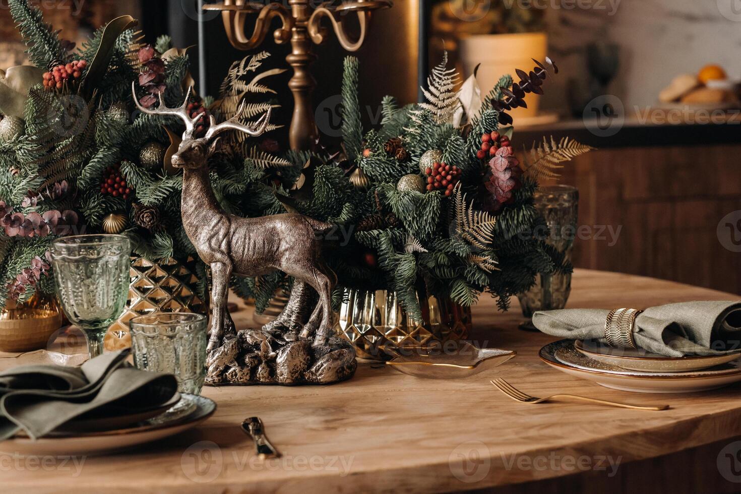 Christmas table decoration, Banquet table with glasses before serving food, Close-up of Christmas dinner table with seasonal decorations, crystal glasses and decorative deer photo