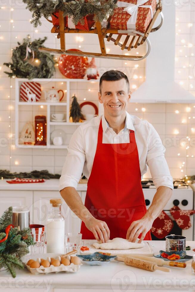 A male chef prepares dough in the Christmas kitchen before the New year photo