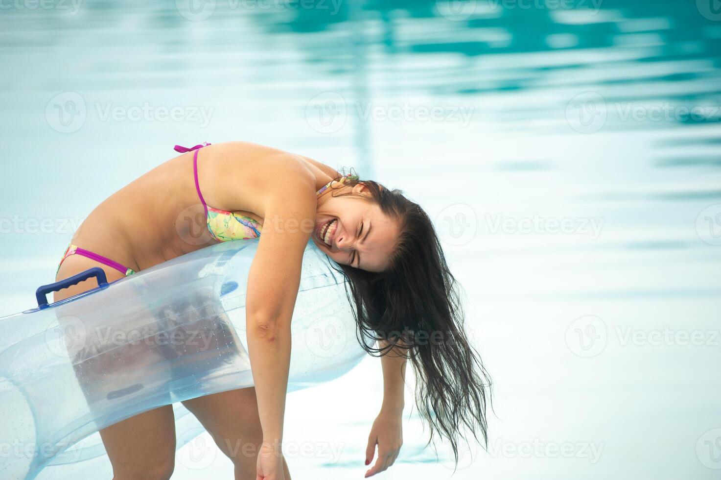 a woman in a bikini with a rubber inflatable circle playing and having a good time in the amusement park pool in the summer photo