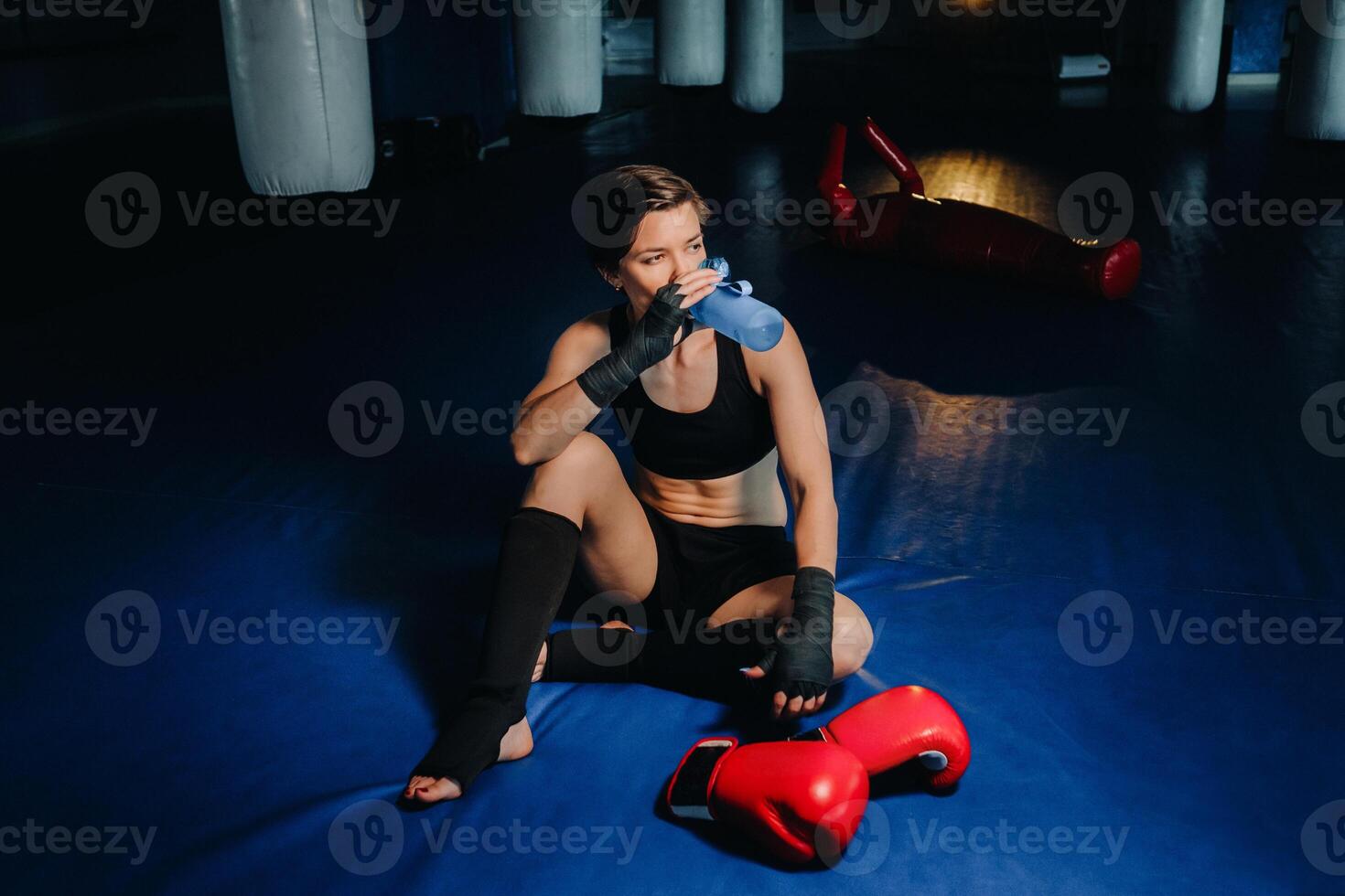 portrait of a female boxer in red gloves in the gym after a workout with a bottle of water photo