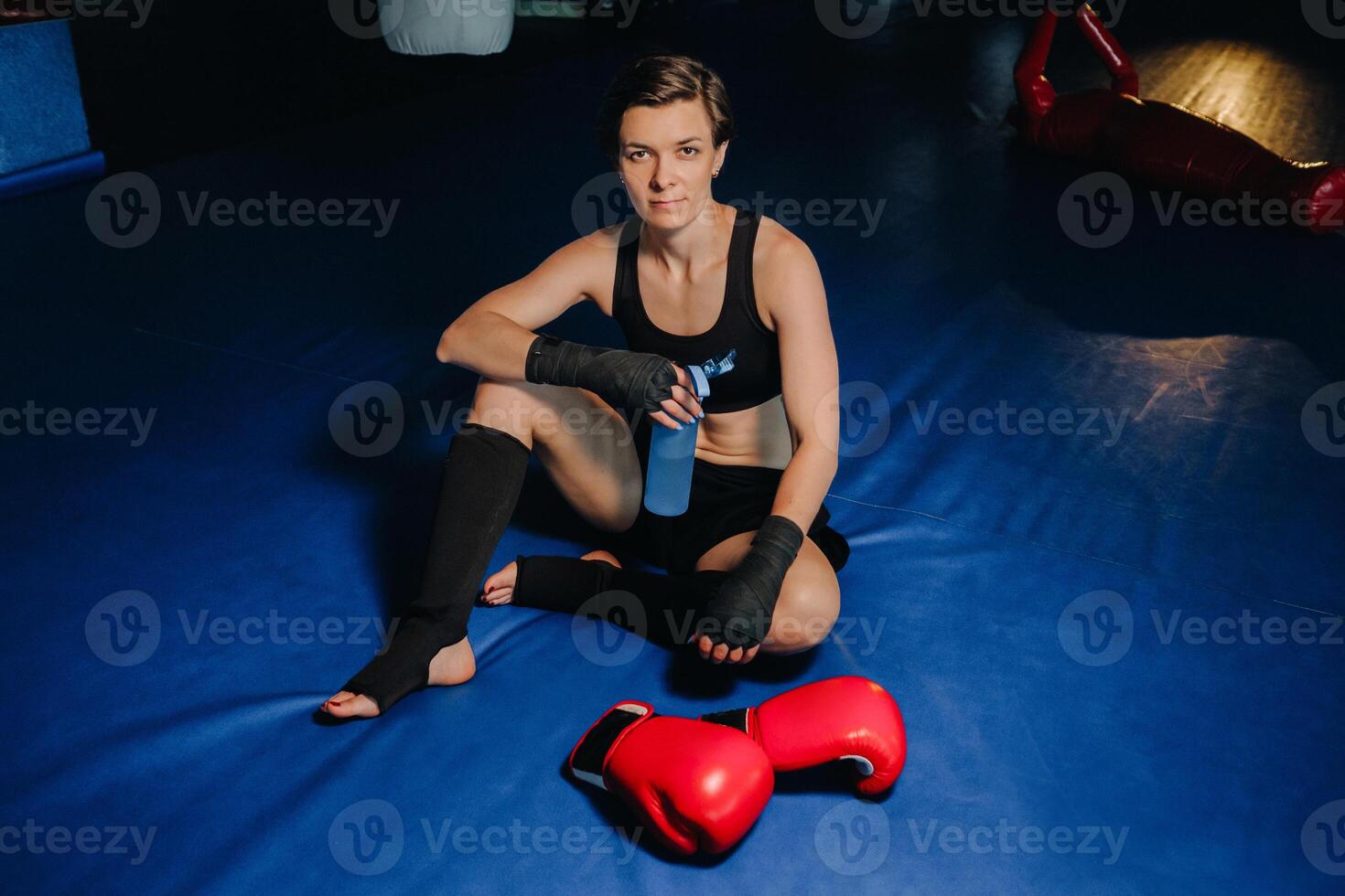 portrait of a female boxer in red gloves in the gym after a workout with a bottle of water photo