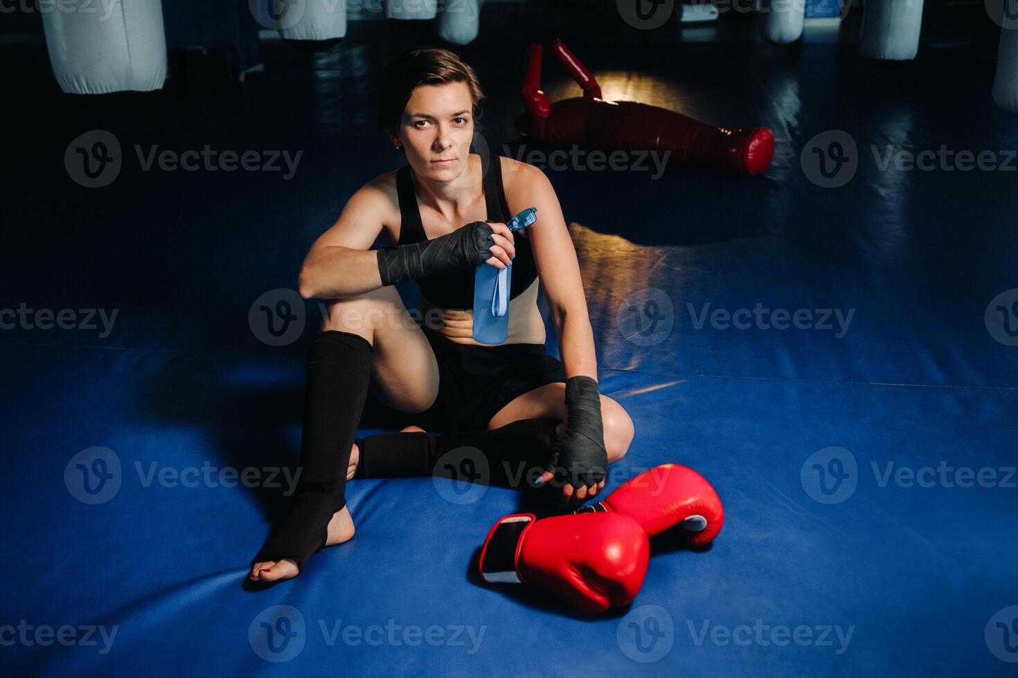 portrait of a female boxer in red gloves in the gym after a workout with a bottle of water photo