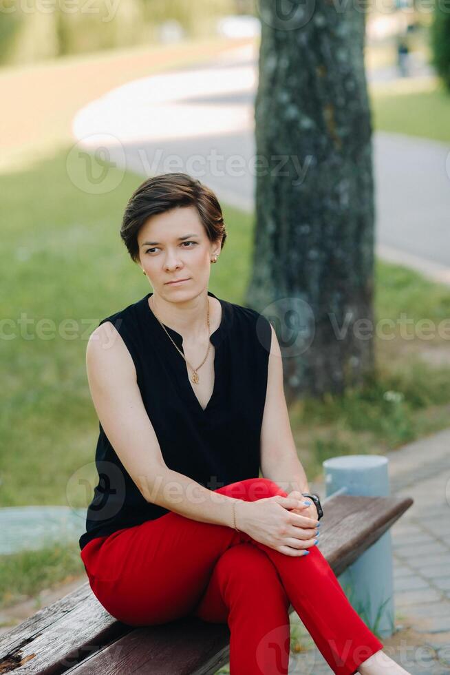 Portrait of a girl in a red suit standing in the alley of the park photo