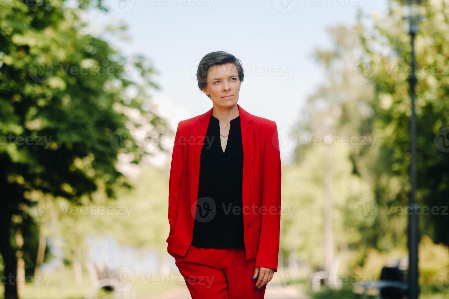 Portrait of a girl in a red suit standing in the alley of the park photo