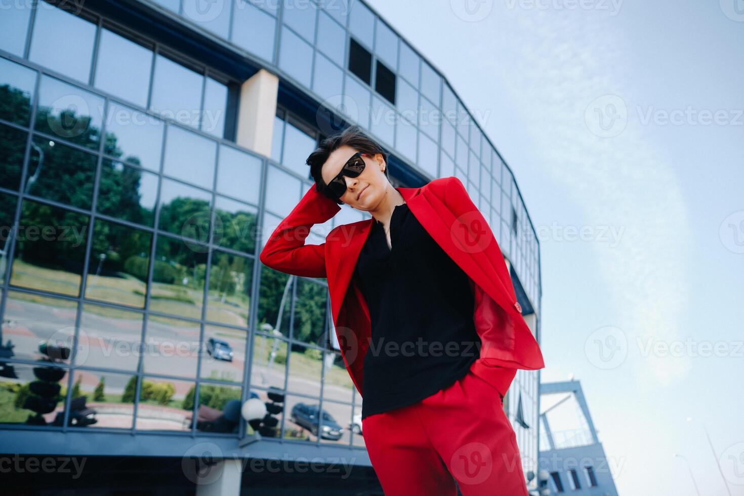 A girl in a red suit stands against the background of a modern building in the city photo