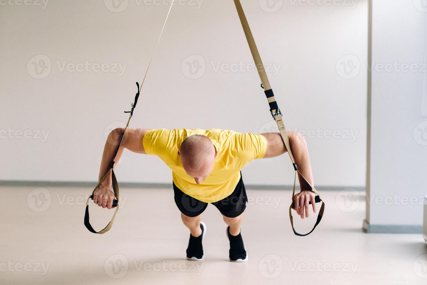 A focused male athlete performing an exercise on functional loops in the gym photo