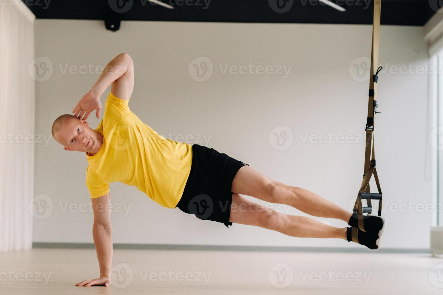 A focused male athlete performing an exercise on functional loops in the gym photo