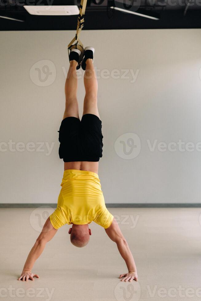 A focused male athlete performing an exercise on functional loops in the gym photo