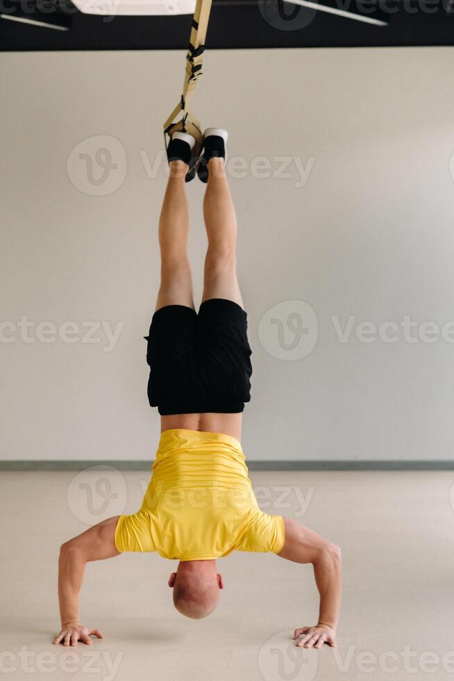 A focused male athlete performing an exercise on functional loops in the gym photo