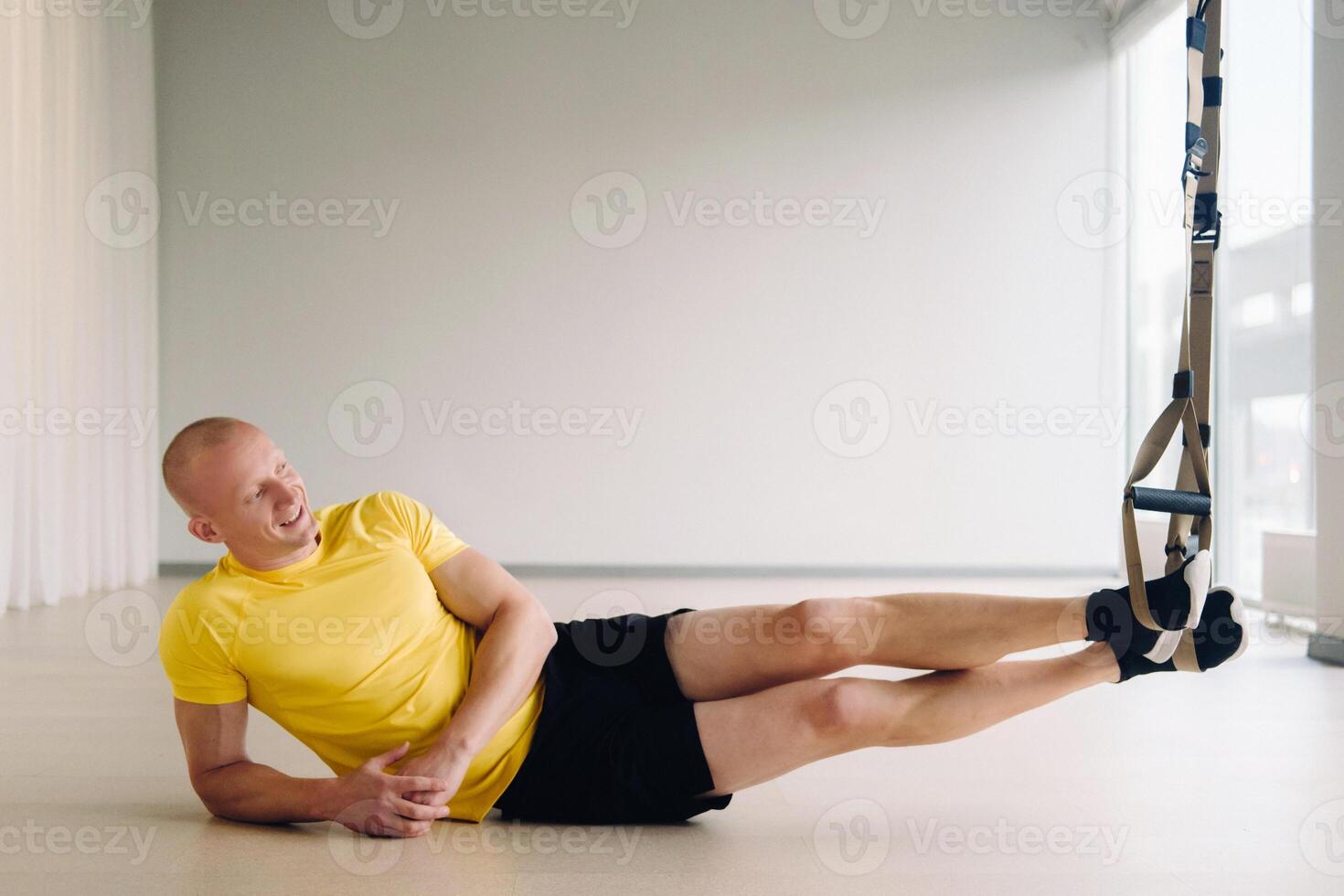 A focused male athlete performing an exercise on functional loops in the gym photo