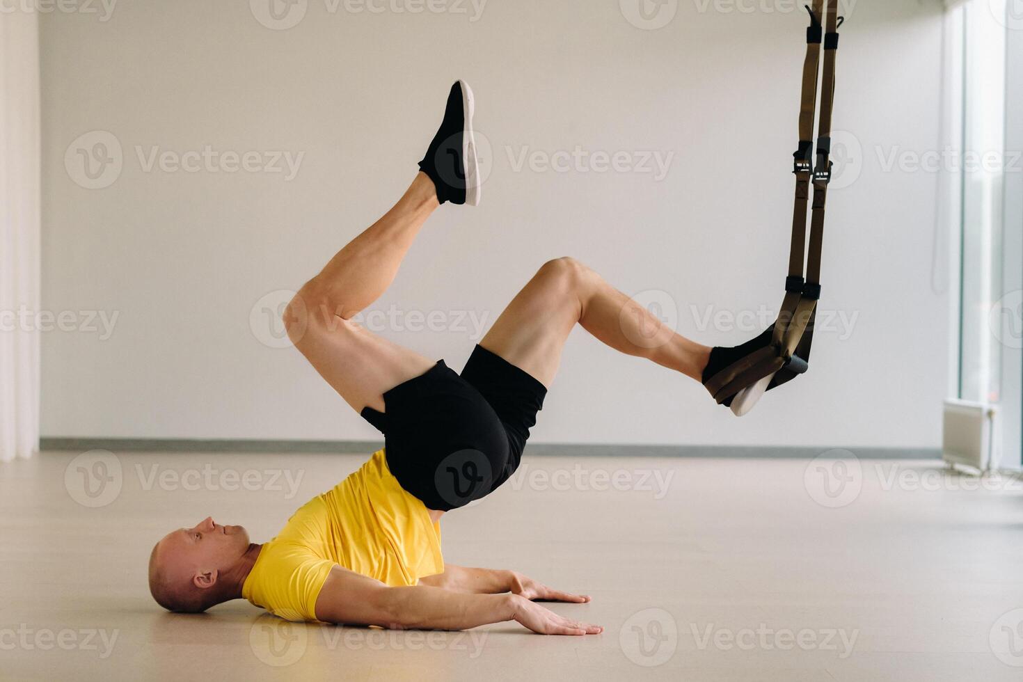 A focused male athlete performing an exercise on functional loops in the gym photo