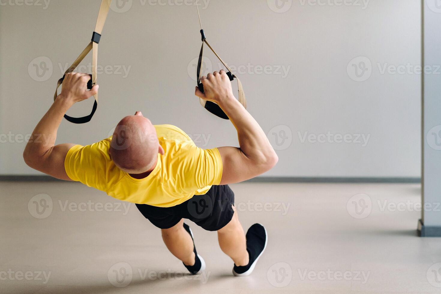 A focused male athlete performing an exercise on functional loops in the gym photo