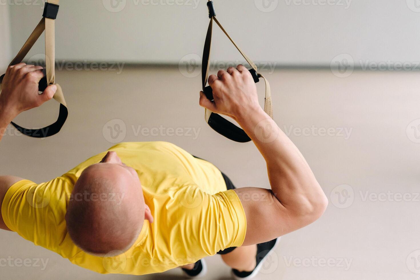 A focused male athlete performing an exercise on functional loops in the gym photo