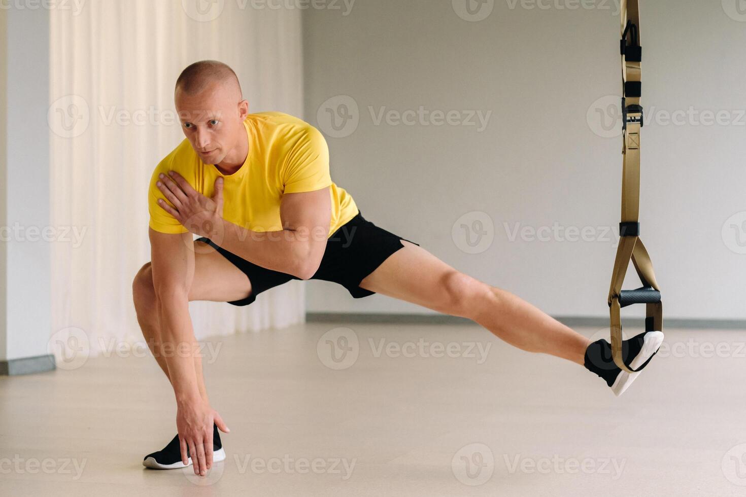 A focused male athlete performing an exercise on functional loops in the gym photo