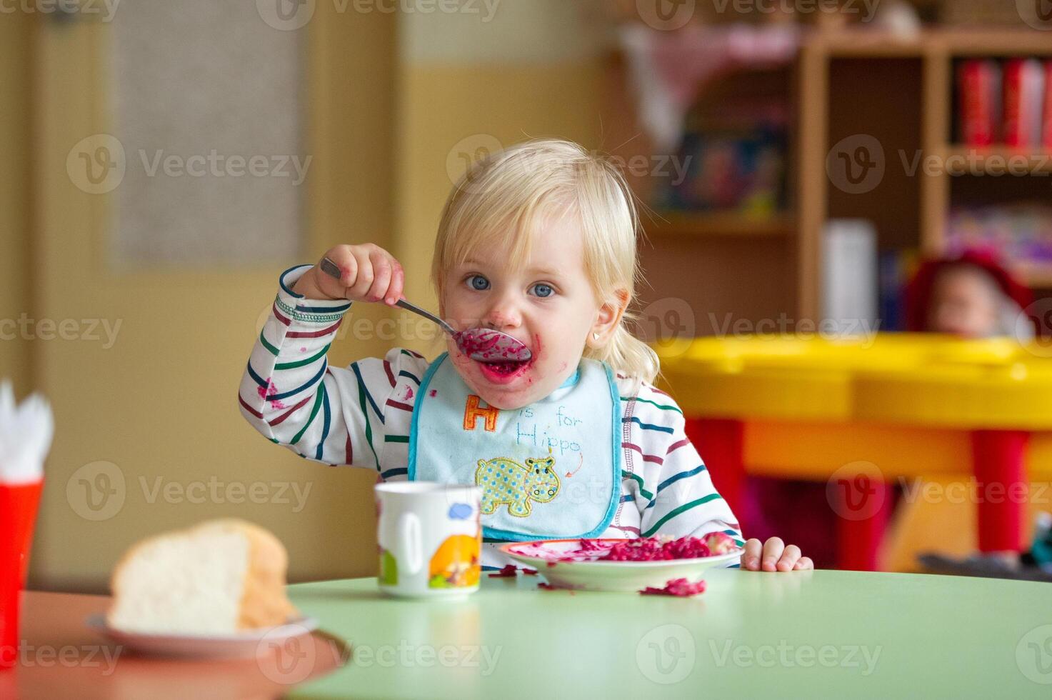 the child eats healthy food in kindergarten or at home and gets dirty photo