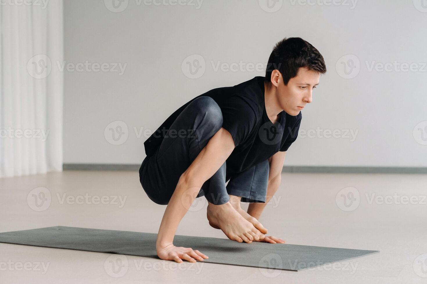A man in a black T-shirt trains lying down doing stretches in the gym photo