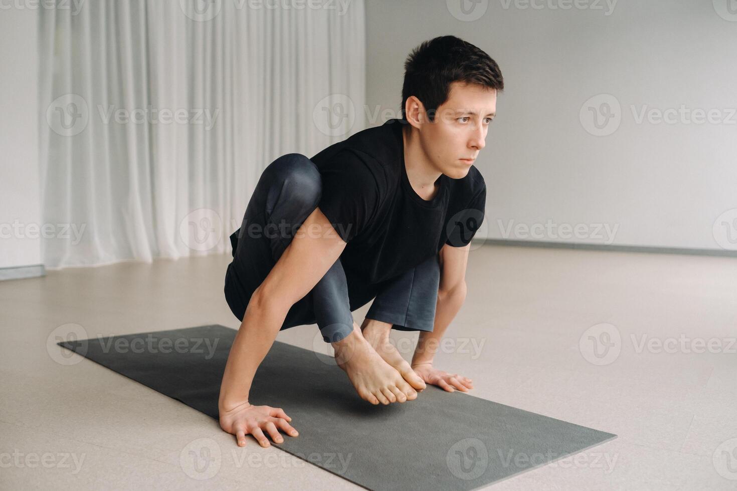 A man in a black T-shirt trains lying down doing stretches in the gym photo