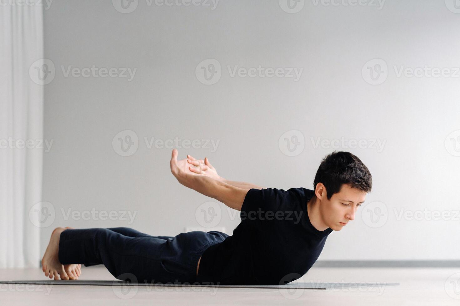 A man in a black T-shirt trains lying down doing stretches in the gym photo