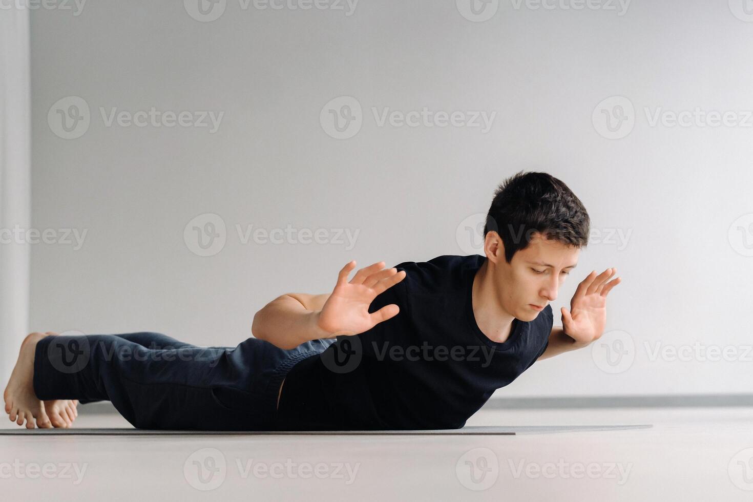 A man in a black T-shirt trains lying down doing stretches in the gym photo