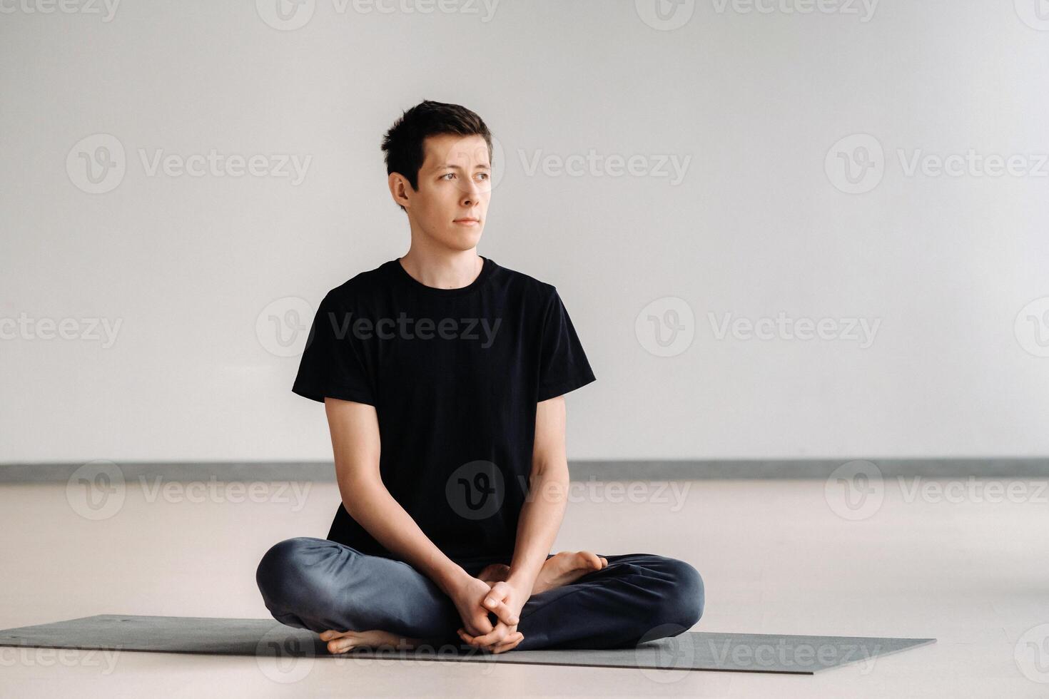 A male athlete in a black T-shirt is sitting in the gym before training and resting photo