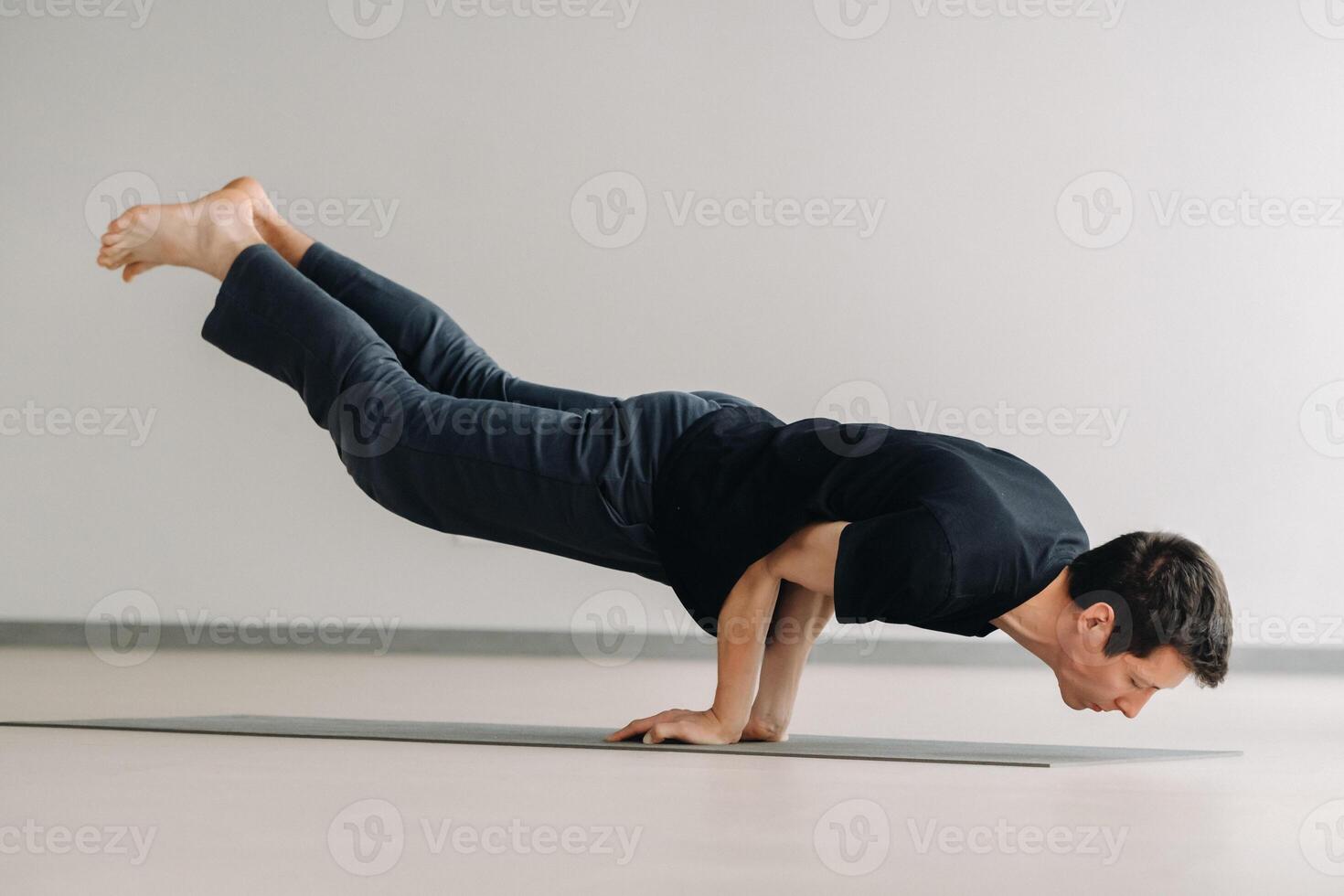 A man in a black T-shirt trains lying down doing stretches in the gym photo