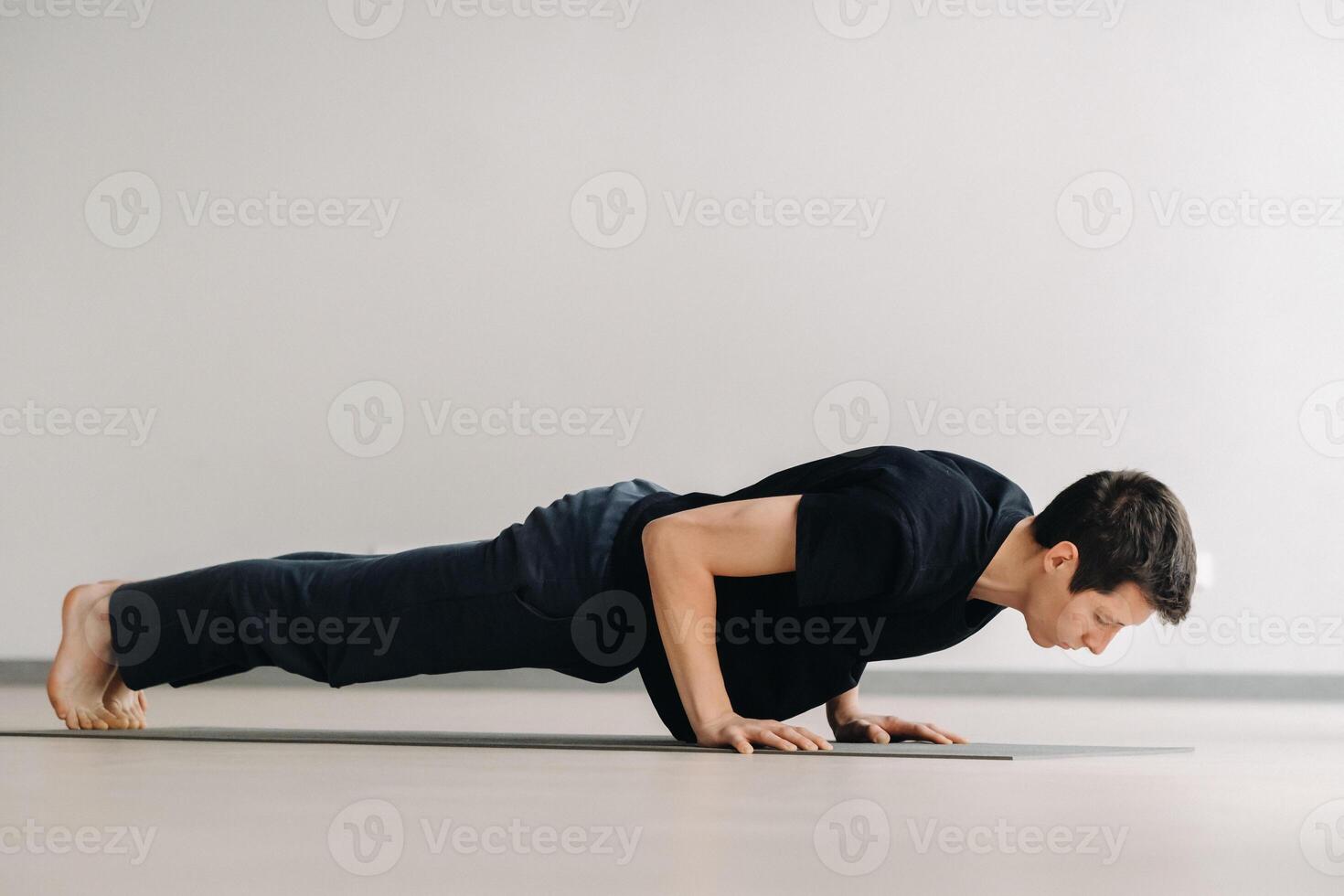 A man in a black T-shirt trains lying down doing stretches in the gym photo