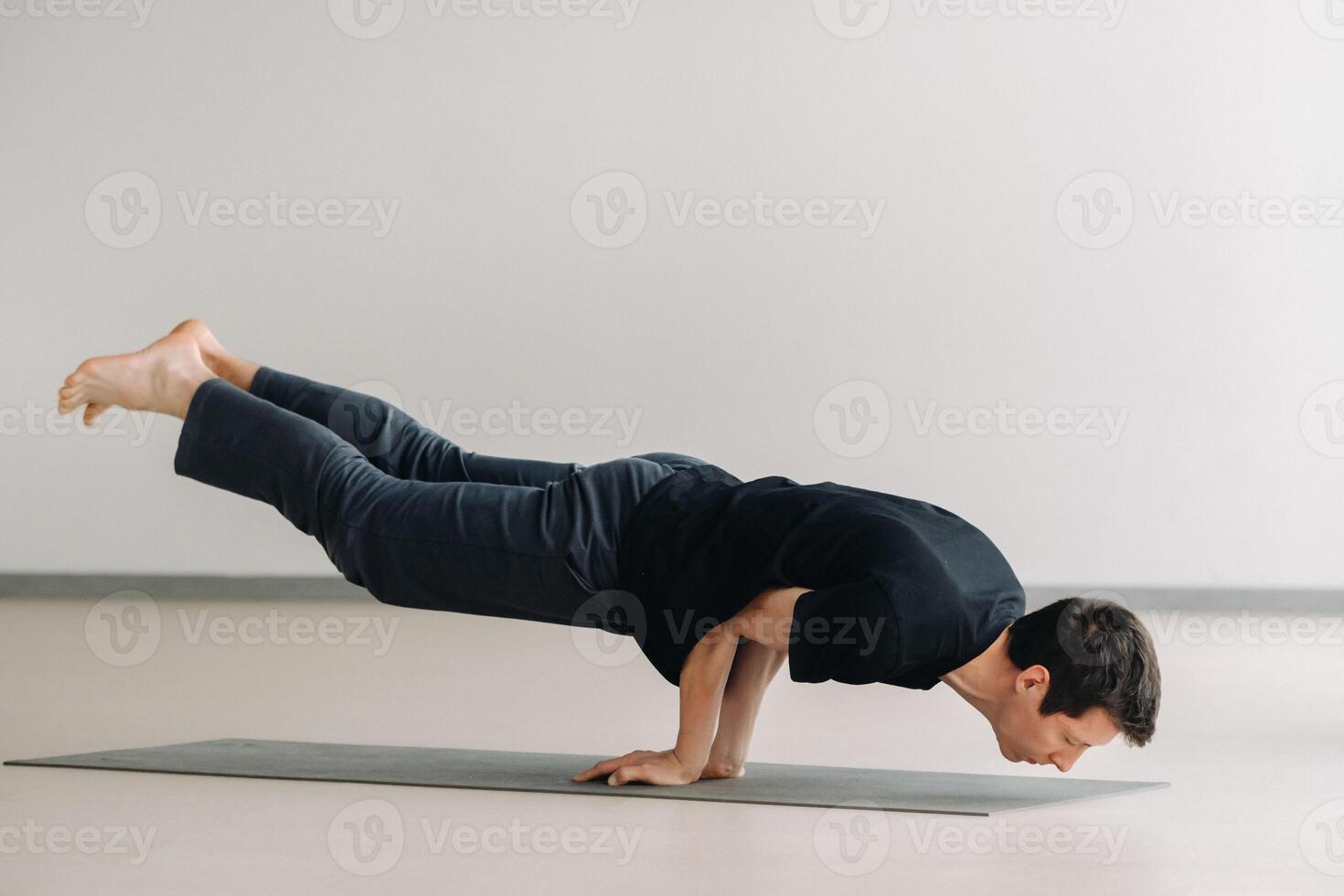 A man in a black T-shirt trains lying down doing stretches in the gym photo