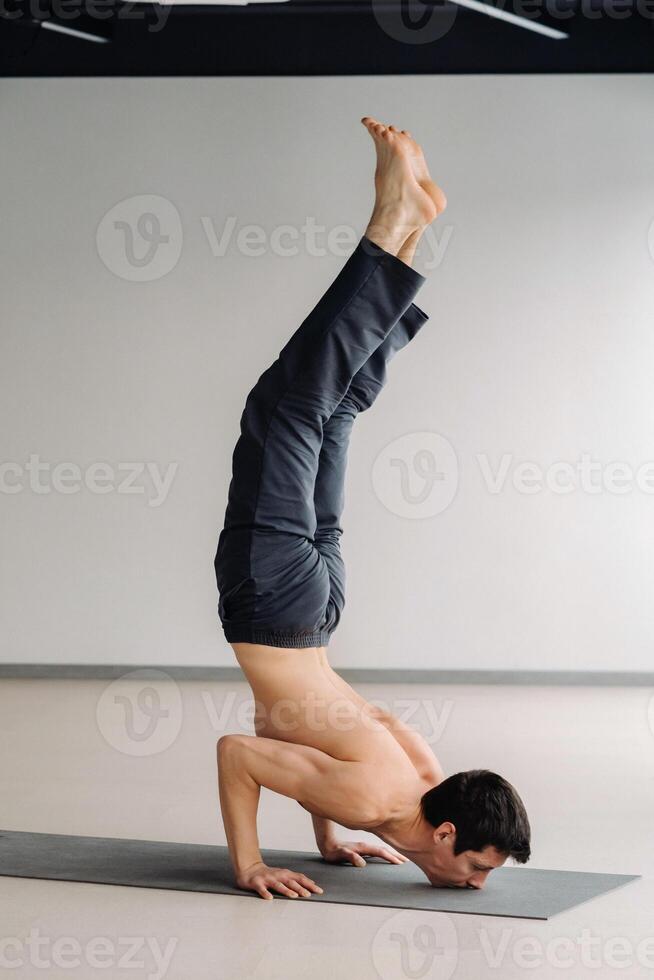 A man in a black T-shirt trains lying down doing stretches in the gym photo