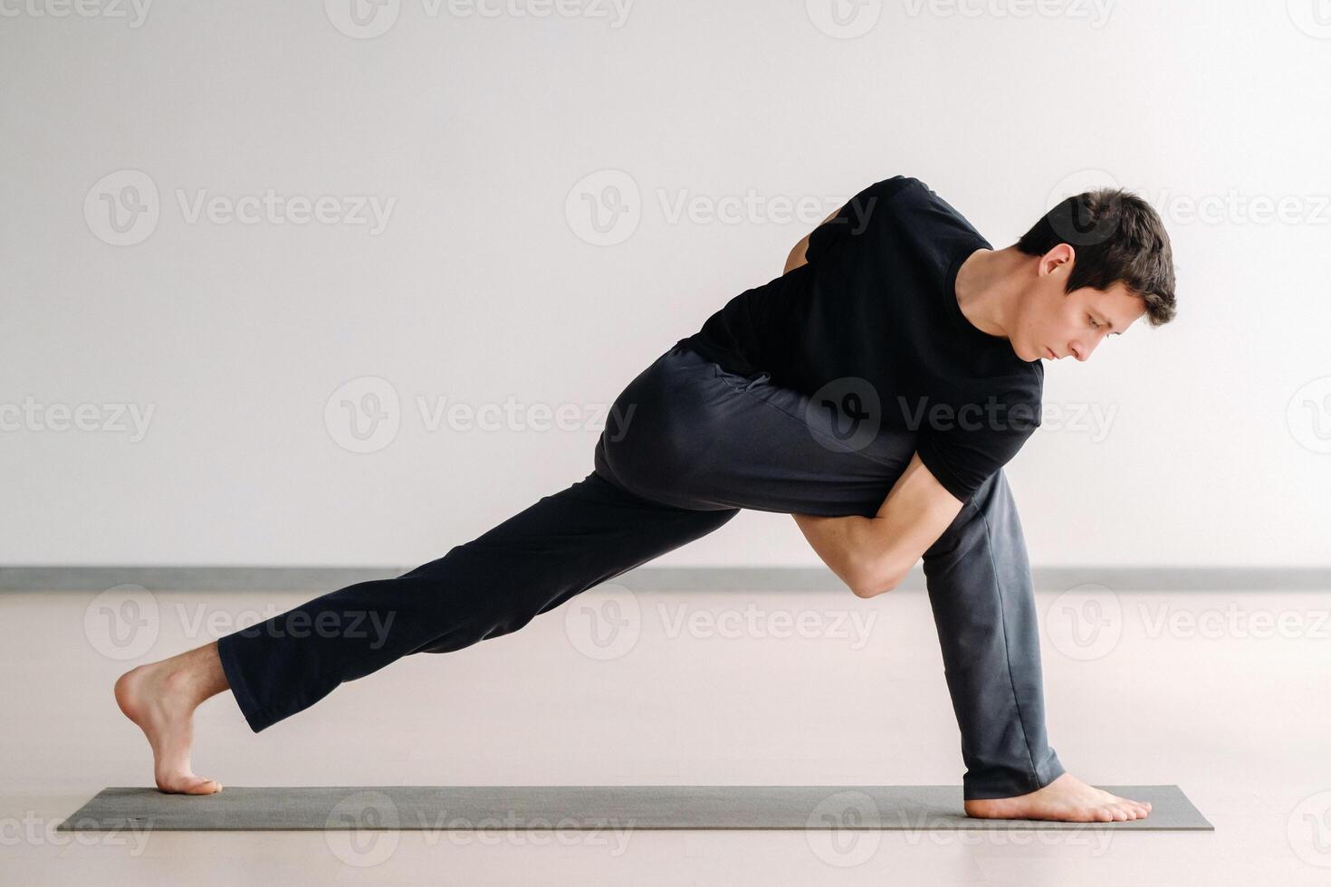 A man in a black T-shirt trains standing up, doing stretching in the gym photo