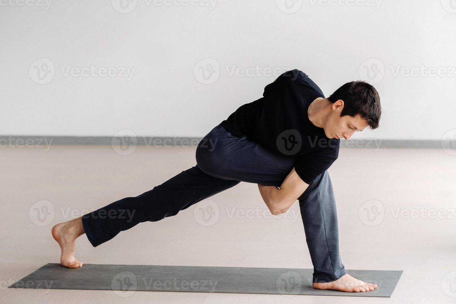 A man in a black T-shirt trains standing up, doing stretching in the gym photo