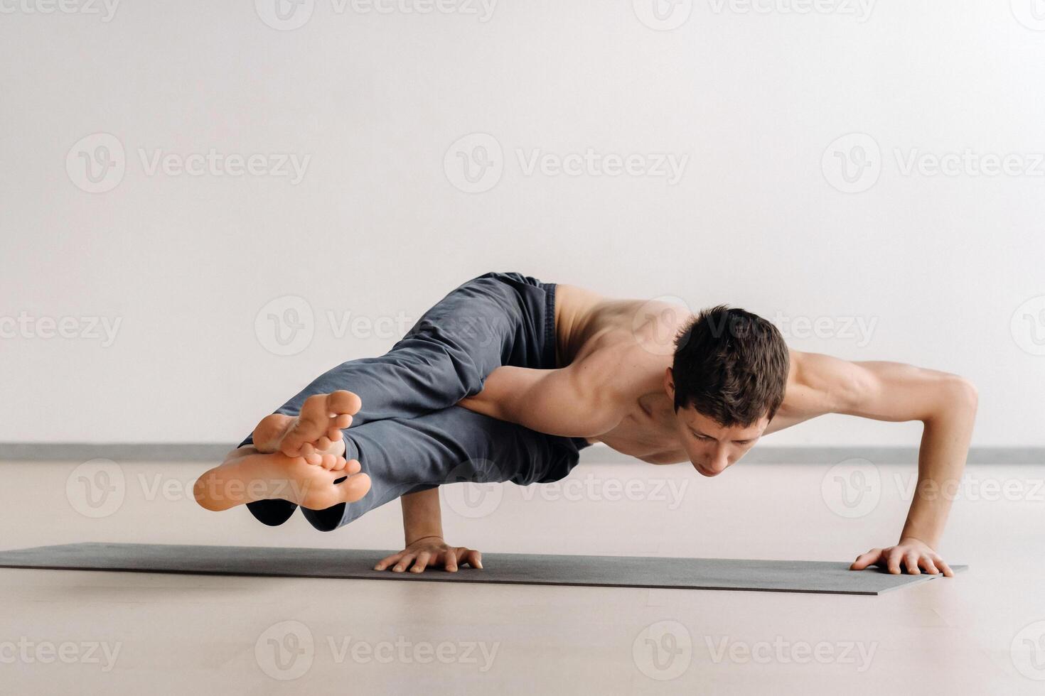 A man with a bony torso trains lying down, doing a handstand in the gym photo
