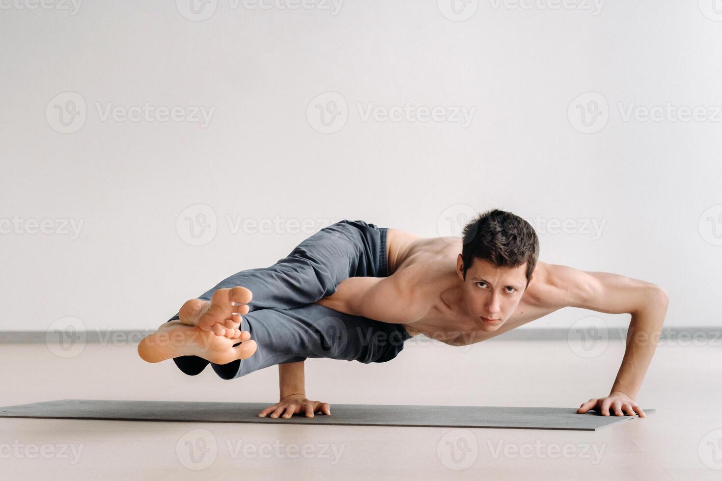 A man with a bony torso trains lying down, doing a handstand in the gym photo
