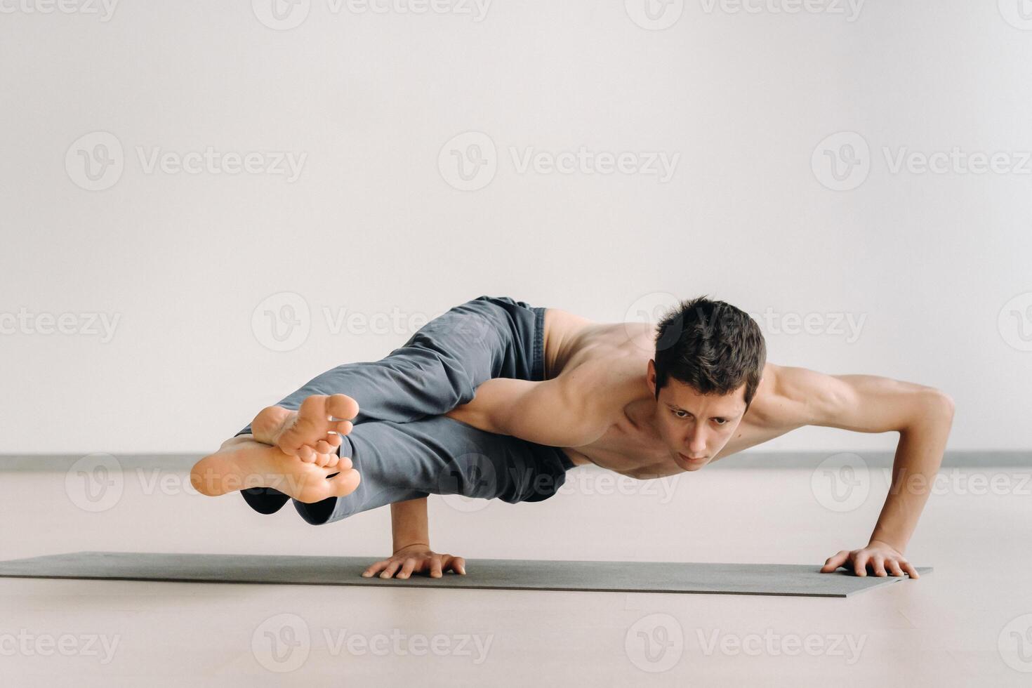 A man with a bony torso trains lying down, doing a handstand in the gym photo