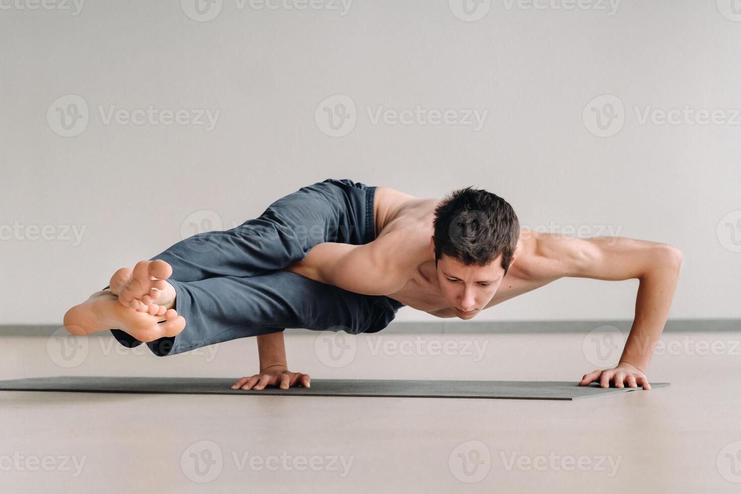A man with a bony torso trains lying down, doing a handstand in the gym photo
