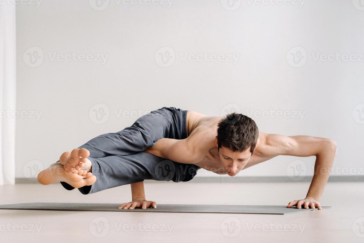 A man with a bony torso trains lying down, doing a handstand in the gym photo