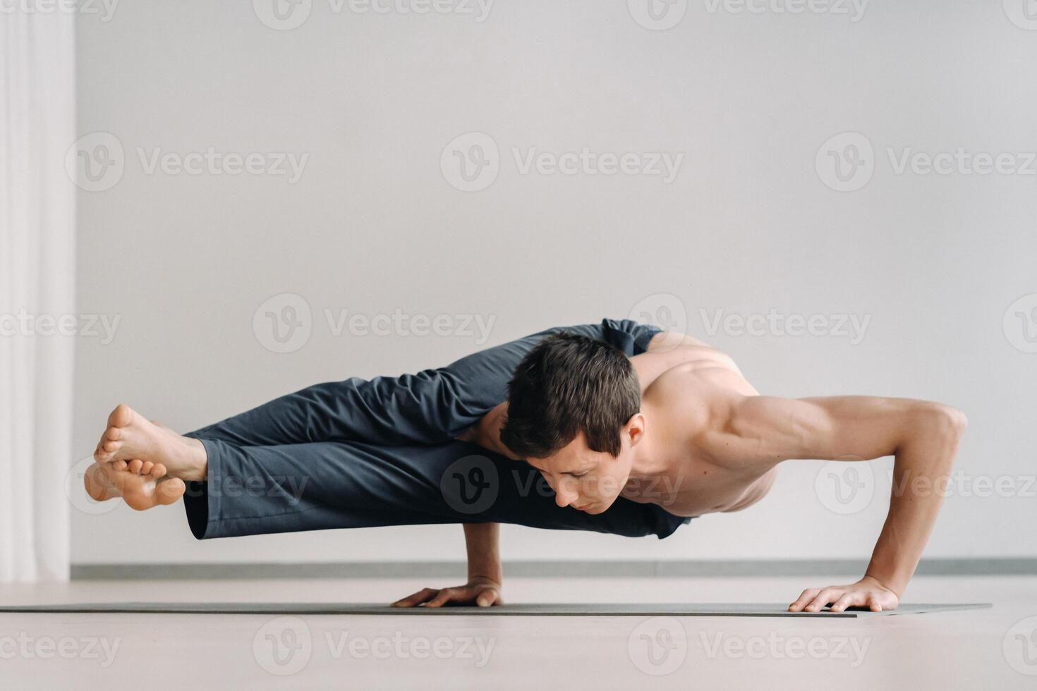 A man with a bony torso trains lying down, doing a handstand in the gym photo