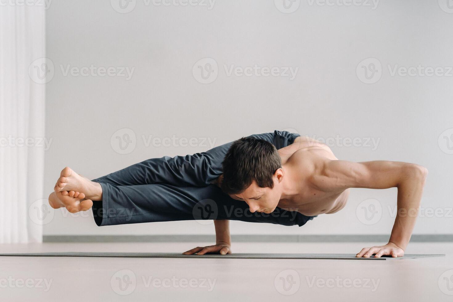 A man with a bony torso trains lying down, doing a handstand in the gym photo