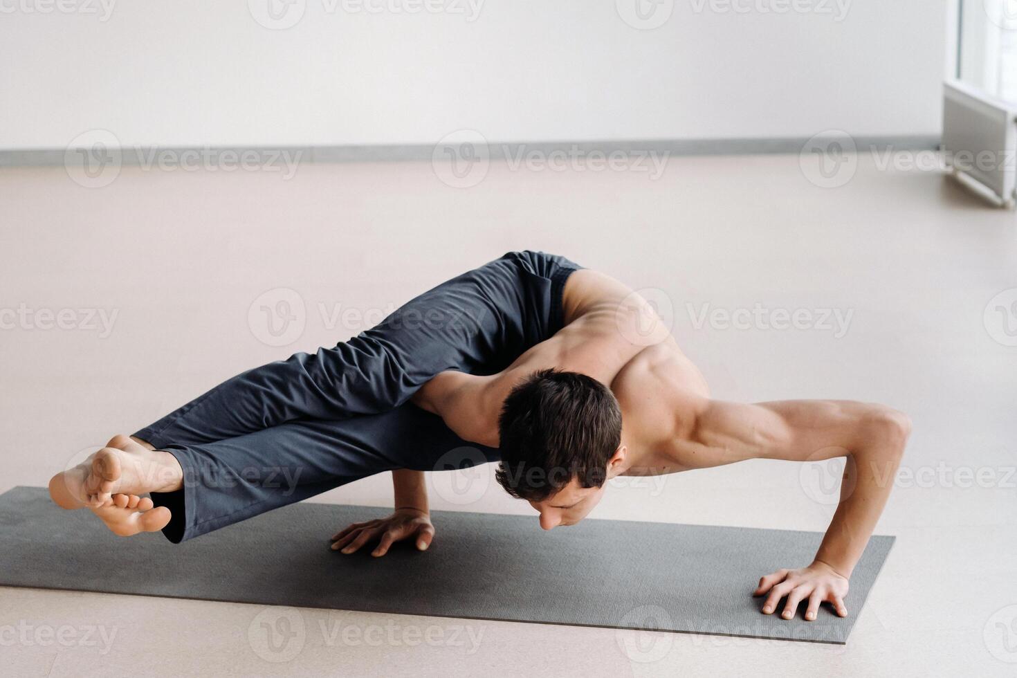 A man with a bony torso trains lying down, doing a handstand in the gym photo