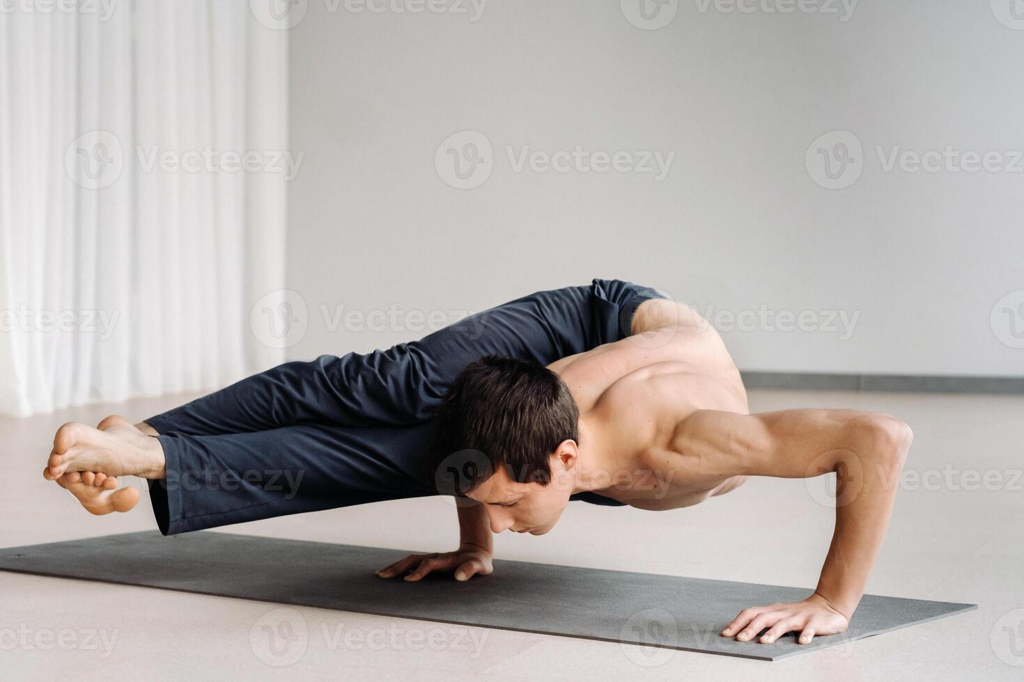 A man with a bony torso trains lying down, doing a handstand in the gym photo