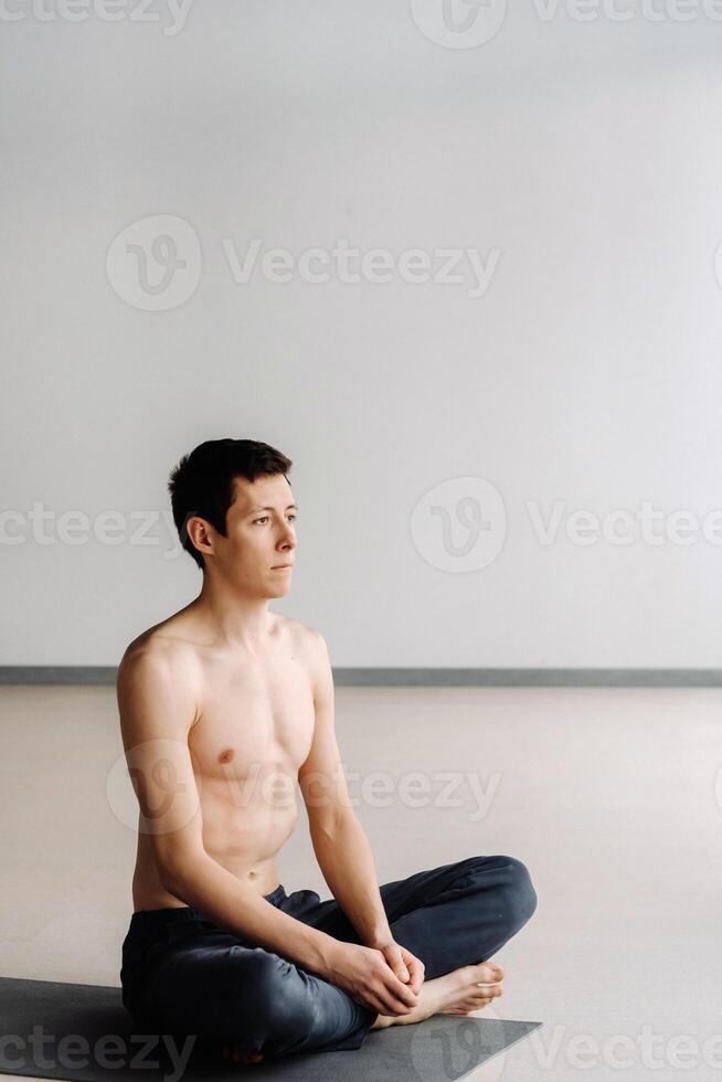 A male athlete with a bare torso is sitting in the gym before training and resting photo