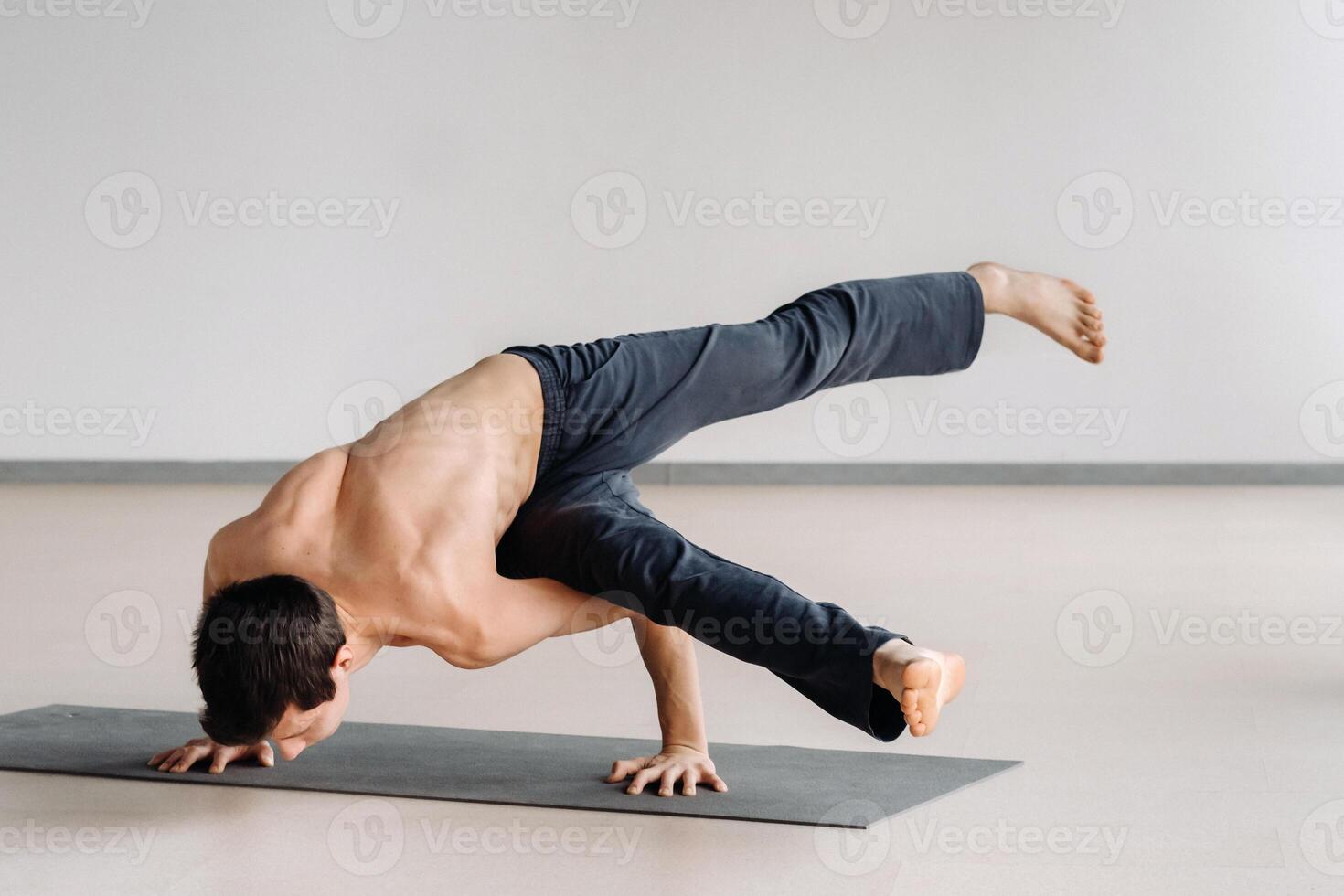 A man with a bony torso trains lying down, doing a handstand in the gym photo