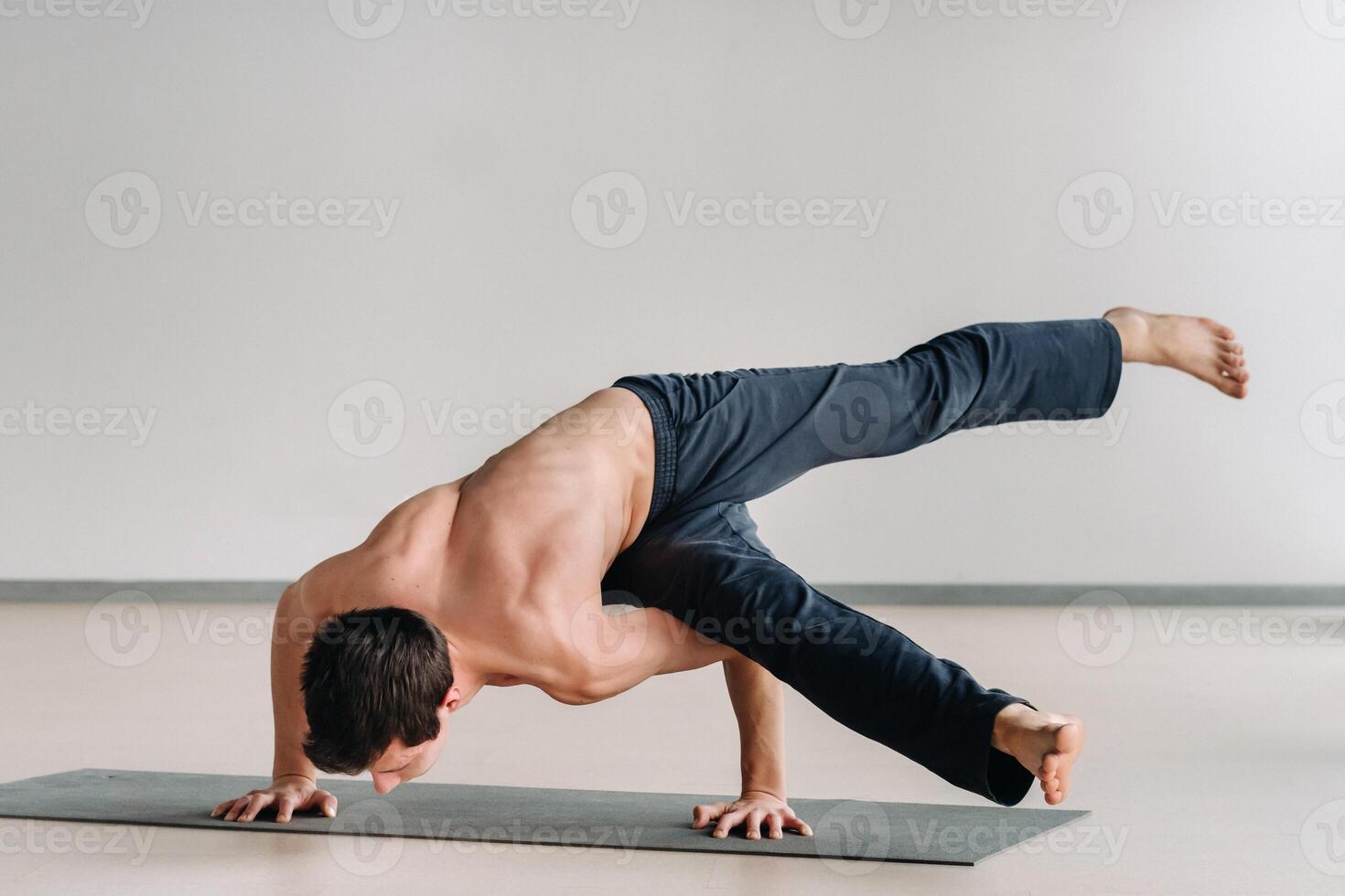 A man with a bony torso trains lying down, doing a handstand in the gym photo