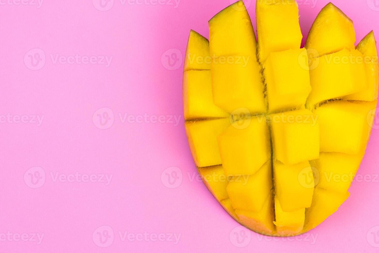 Fresh ripe mango on a pink background. Half a sliced mango on a pink background photo