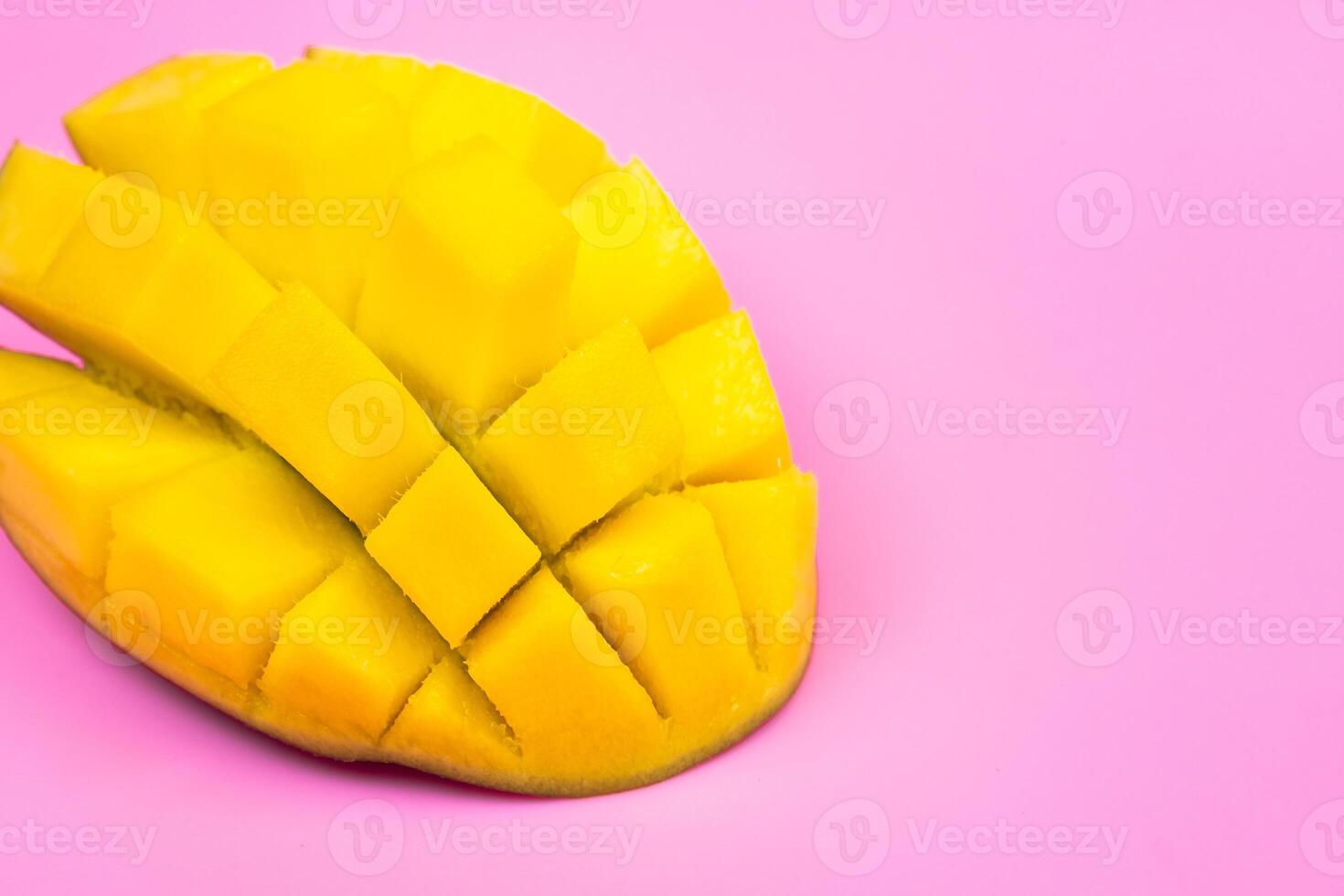 Fresh ripe mango on a pink background. Half a sliced mango on a pink background photo