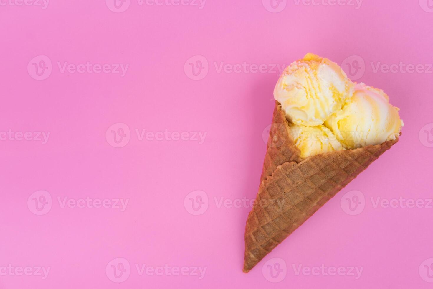 Fruit-scented ice cream balls in a waffle cone on a pink background. photo