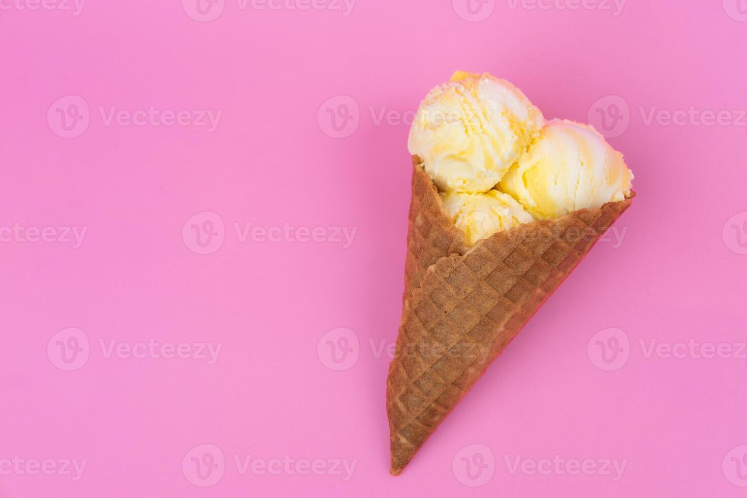 Fruit-scented ice cream balls in a waffle cone on a pink background. photo