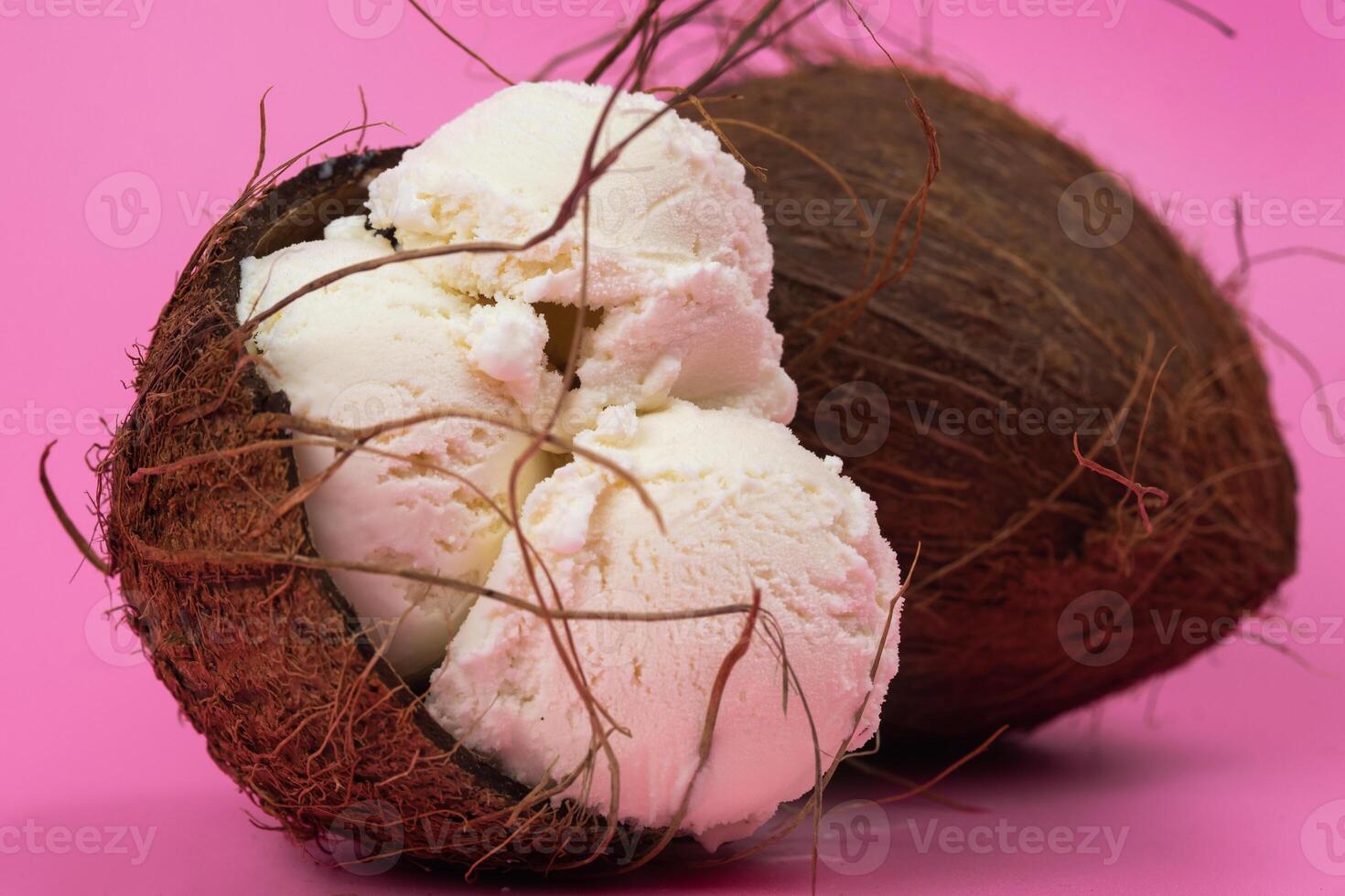 Vanilla ice cream balls in an empty coconut decorated with mint leaves on a pink background photo