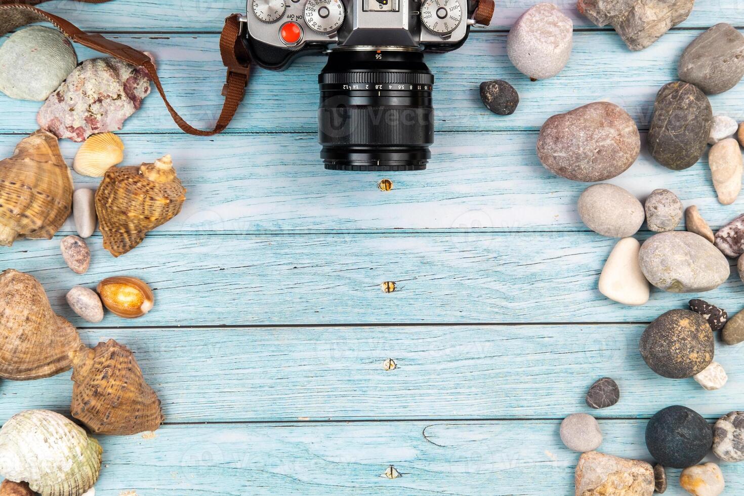 camera and seashells on a blue wooden background.Marine theme photo